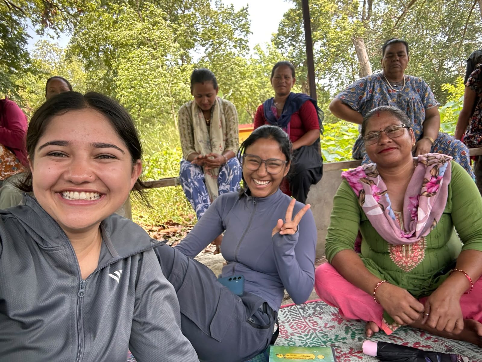 Abhishu Neupane and Shejal Pradhan sitting with a community forest women's group