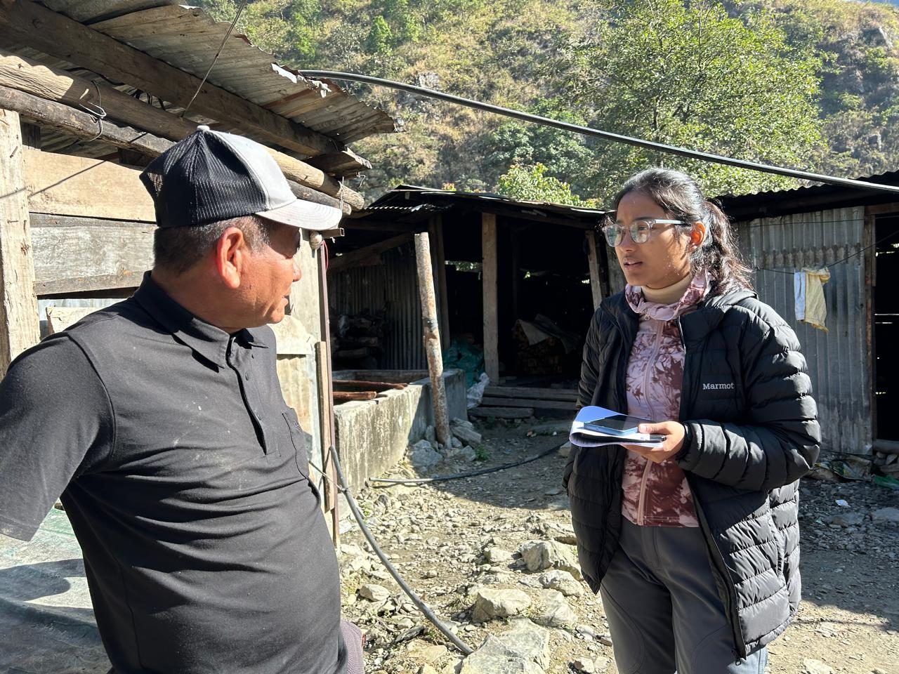Shejal Pradhan interviewing a man outside a farm shed