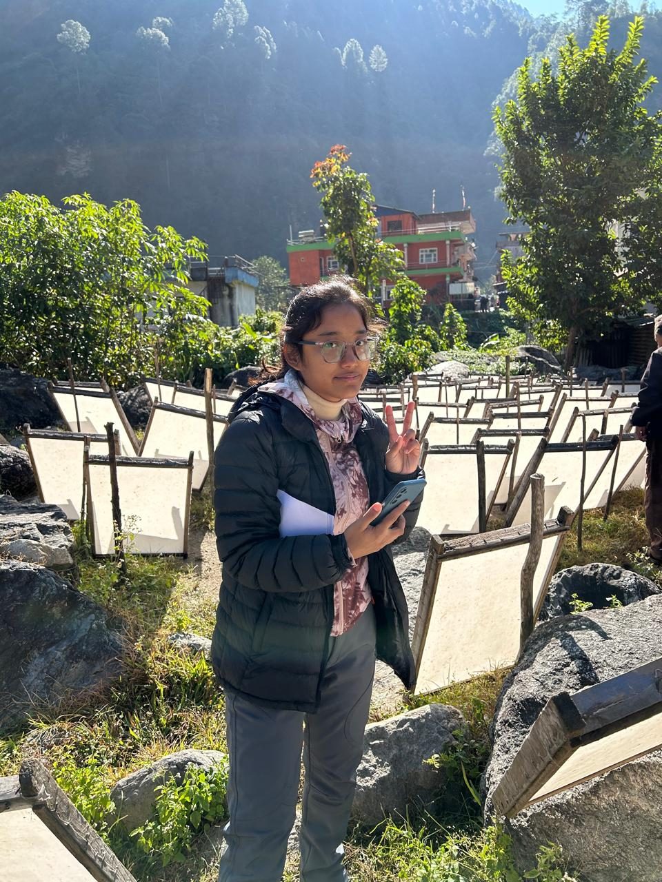 Shejal Pradhan among frames of handmade lokta paper drying in the sun